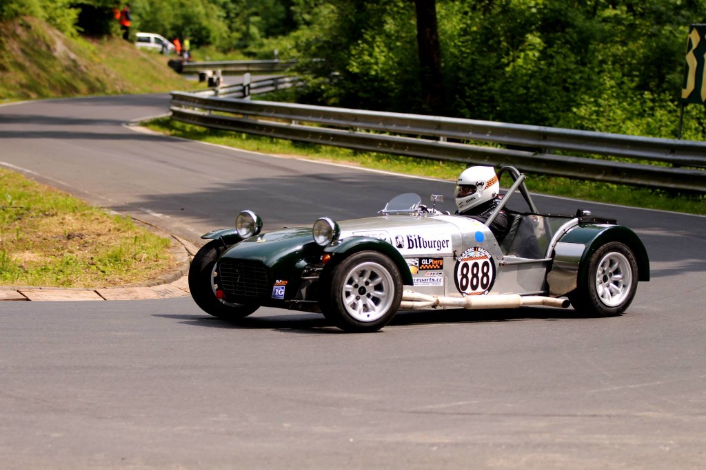 Ein Rennwagen mit der Nummer 888, gelenkt von einem Fahrer mit Helm, rast auf der von Bäumen gesäumten Rennstrecke des Wolsfelder Bergrennens um eine Kurve.